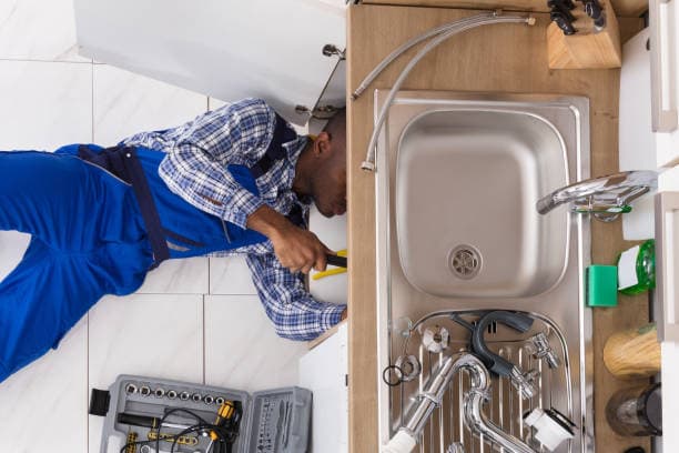 Loodgieter controleert de warmwateraansluitingen onder een wastafel